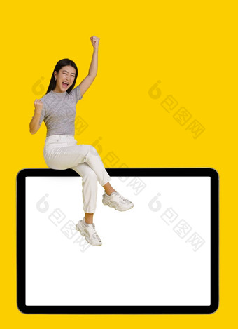 赢得手势兴奋亚洲女孩坐着巨大的巨大的数字平板电脑白色空白屏幕孤立的黄色的背景模拟产品放置移动应用程序广告复制空间
