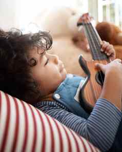 弹奏梦想拍摄可爱的年轻的男孩玩吉他卧室首页
