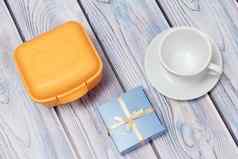 塑料黄色的午餐盒子礼物杯飞碟木背景
