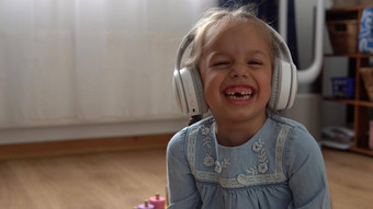 孩子听音乐大白色耳机快乐学前教育没有牙齿的女孩年相机离开房间内部孩子微笑笑着说显示舌头首页童年教育