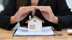 裁剪图像女人手庇护小房子模型真正的房地产租赁保险购买维护概念