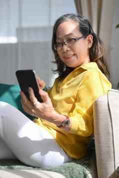 有吸引力的成熟的女人休息舒适的沙发聊天在线社会网络聪明的电话