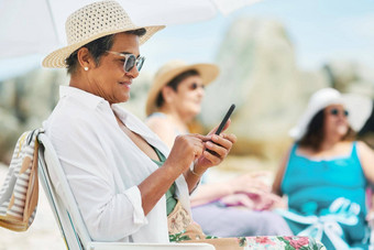 发<strong>送</strong>自拍<strong>孩子</strong>们拍摄成熟的女人坐着手机一天海滩朋友