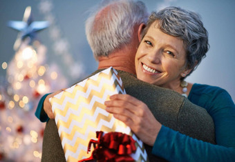 圣诞节拥抱礼物拍摄成熟的女人给合作伙伴拥抱礼物