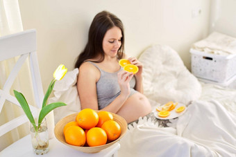 年轻的美丽的怀孕了女人橙子首页坐着床上