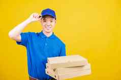 交付服务男人。站微笑穿蓝色的t恤帽统一的持有给食物订单披萨纸板盒子