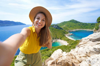 年轻的旅行者女人采取自拍图片港口到的观点科孚岛希腊