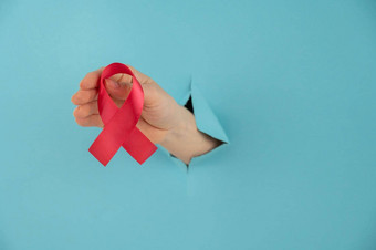 女人的手红色的弓棒洞蓝色的背景象征战斗艾滋病