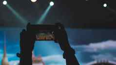 人持有聪明的手机拍摄音乐会捕获视频音乐会电话相机明亮的关注的焦点灯
