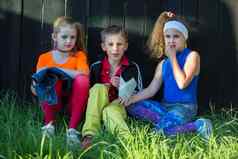 美丽的模型孩子们明亮的衣服坐草木栅栏