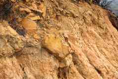 特写镜头摇摇欲坠污垢山腰棕色（的）变形石头粘土悬崖墙粗糙的橙色山环境Copyspace自然场景背景户外表面抱石攀爬