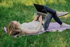 横幅年轻的女孩作品移动PC新鲜的空气公园坐着草坪上概念远程工作工作自由职业者女孩需要课程移动PC微笑
