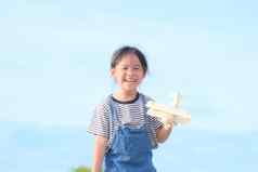 快乐孩子玩玩具飞机蓝色的夏天天空背景可爱的女孩运行草地阳光明媚的一天玩具飞机手童年梦想想象力概念