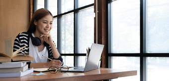 微笑亚洲年轻的女耳机移动PC屏幕听学习在线课程快乐中国人业务女人耳机视频调用客户服务