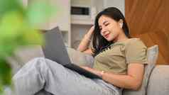 休闲年轻的女人穿耳机看在线电影冲浪互联网移动PC生活房间