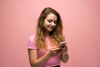 微笑年轻的女人女孩粉红色的t恤移动<strong>电话</strong>打字<strong>短信</strong>消息朋友孤立的粉红色的墙背景工作室人生活方式概念模拟复制空间