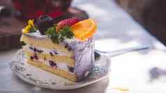 关闭片生日水果蛋糕板紫罗兰色的美味的奶油层