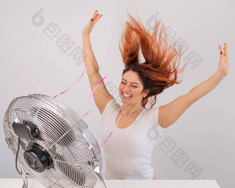 快乐的高加索人女人享受风吹<strong>电风扇</strong>白色背景