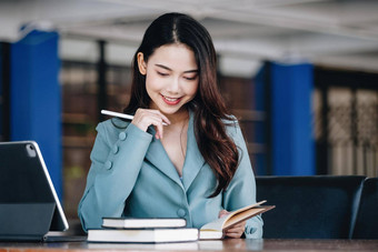 女企业家女商人显示微笑脸阅读书发展中金融投资策略操作电脑平板电脑工作木表格