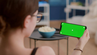 特写镜头年轻的女人持有水平智能手机绿色屏幕看影响者视频博客