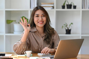 友好的亚洲女人办公室工人问候的同事们工作电脑移动PC