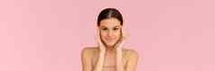 皮肤护理女人美脸触碰健康的面部皮肤微笑女模型相机微笑粉红色的背景网络横幅