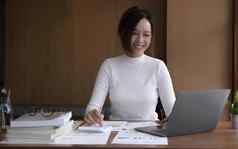 有吸引力的年轻的亚洲女商人办公室工人工作桌子上移动PC电脑分析金融数据