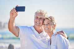 快乐成熟的高加索人夫妇享受新鲜的空气假期海滩手机微笑退休夫妇拥抱采取自拍