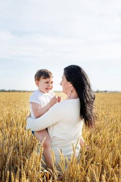 快乐家庭妈妈。婴儿孩子走小麦场家庭肖像