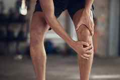 特写镜头运动员膝盖联合疼痛手适合男人。触碰膝盖疼痛强大的男人。痛膝盖健身房健美运动员伤害膝盖受伤活跃的男人。膝盖扭伤