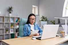 年轻的亚洲女人研究在线坐着办公室写作讲座笔记笔记本移动PC研究