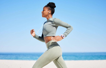 适合活跃的非洲美国女人听<strong>音乐</strong>耳机运行海滩锻炼集中黑色的运动员<strong>培训</strong>锻炼手机跟踪进步