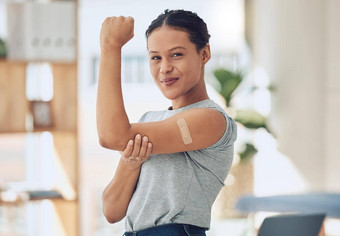 年轻的快乐混合比赛女人显示持有手臂邦迪牌创可贴疫苗美丽的自信年轻的女人玩显示肌肉科维德疫苗