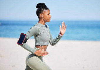 适合活跃的非洲美国女人听音乐耳机运行海滩锻炼集中黑色的运动员培训锻炼手机跟踪进步