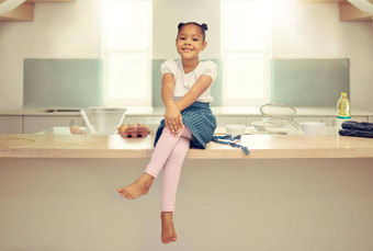 肖像可爱的年轻的混合比赛女孩坐着厨房计数器围裙微笑拉美裔女孩微笑坐着烘焙首页享受烹饪厨房