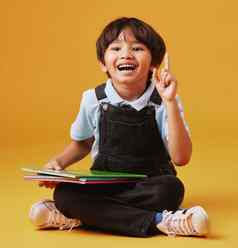 肖像可爱的亚洲男孩坐着地板上阅读橙色背景快乐内容集中教育可爱的孩子的想法