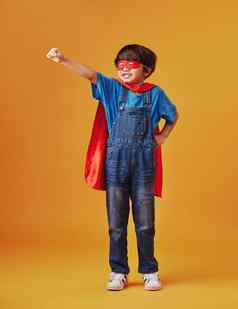 可爱的亚洲男孩穿面具角假装超级英雄橙色工作室背景可爱的快乐男孩假装字符万圣节