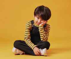 亚洲男孩伤心抑郁坐着地板上摆姿势橙色Copyspace背景可爱的混合比赛孩子添加无聊抑郁