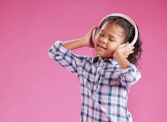 漂亮的混合比赛女孩卷曲的头发听音乐穿耳机粉红色的Copyspace背景工作室非洲孩子唱歌首歌
