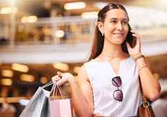 时尚的年轻的混合比赛女人会说话的手机购物疯狂购物中心女享受零售治疗连接智能手机快乐购物狂持有袋使调用朋友出售