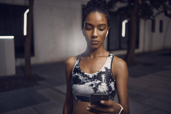 适合年轻的混合比赛女人听<strong>音</strong>乐无线耳机手机采取打破锻炼在户外集中女运动员发<strong>短信</strong>健身应用程序在线浏览社会媒体看锻炼教程