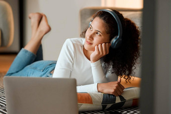 女人做梦听音乐年轻的女人听音乐耳机移动PC女孩说谎地板上思考年轻的女人享受音乐电脑首页