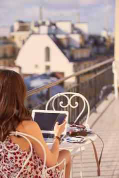 遵循令人惊异的巴黎风景拍摄女人智能手机移动PC早餐阳台公寓俯瞰巴黎法国