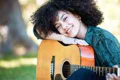 微笑年轻的音乐家休息声吉他玩享受一天公园快乐拉美裔女人卷曲的非洲式发型头发玩音乐吉他花园