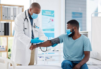 医生检查血压力病人袖口监控非洲美国医生阅读病人血压力医疗病人穿面具保护科维德