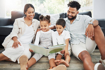 混合比赛家庭阅读书地板上首页拉美裔妈妈。父亲教学儿子女儿读哥哥妹妹学习读父母