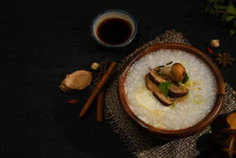 大米粥大米粥粥香菇蘑菇煮熟的蛋切片姜片葱黑色的木表格早餐