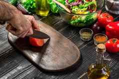 男人的手削减成熟的红色的西红柿夏天健康的蔬菜沙拉木董事会垂直