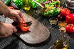男人的手削减成熟的红色的西红柿夏天健康的蔬菜沙拉木董事会垂直