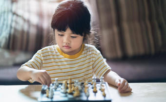 亚洲婴儿玩国际象棋生活房间首页聪明的孩子时尚孩子们天才孩子聪明的游戏棋盘婴儿活动概念